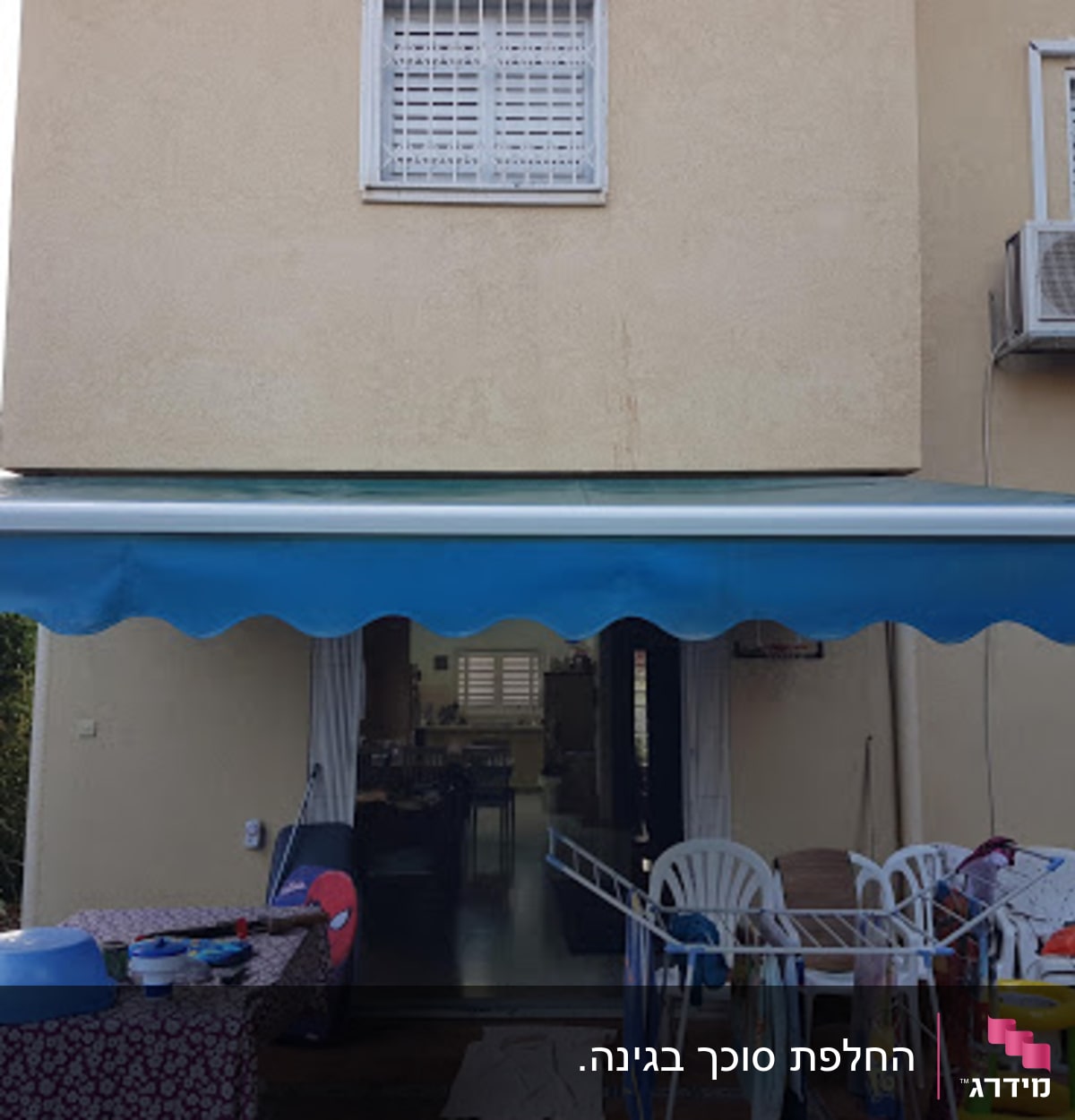 סוכך כחול מותקן מעל מרפסת עם רהיטים